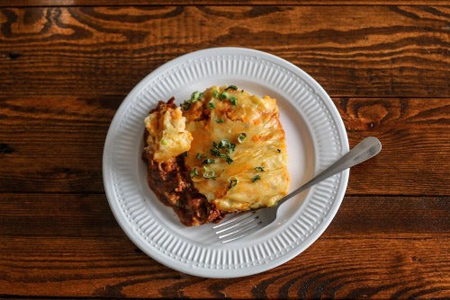 Our version of Shepherd’s Pie is much like the traditional British version, rich, protein filled with lean ground beef savored in flavors of onions, garlic, carrots, English peas, tomatoes, house seasoning and topped with a mashed potato crust.